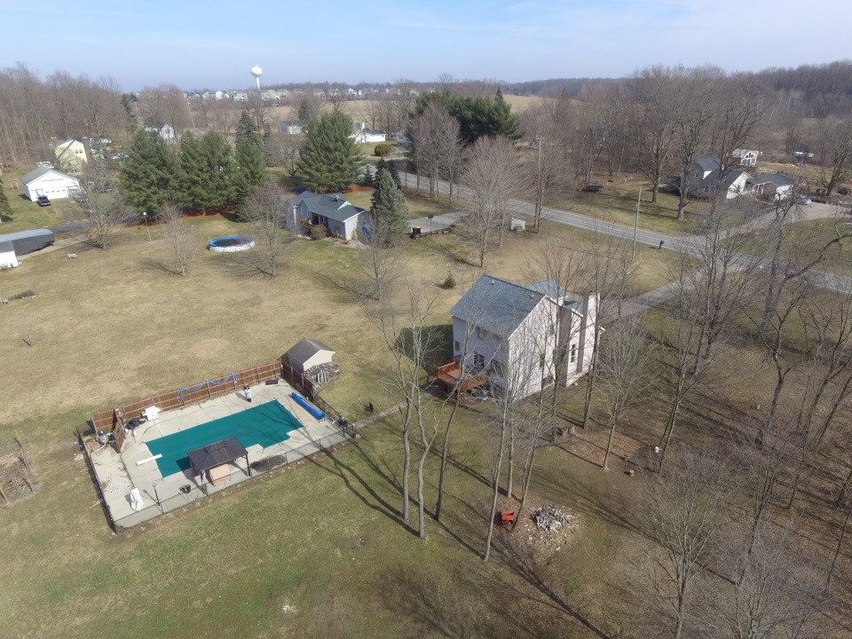 Drone photo of a house, yard, and pool, showcasing property for marketing, construction, and design projects.
