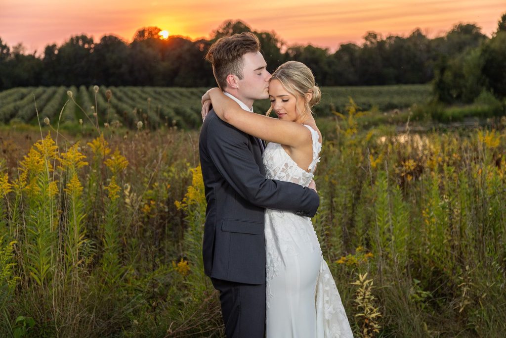Romantic sunset photo of a bride and groom overlooking a vineyard venue, capturing timeless wedding memories.