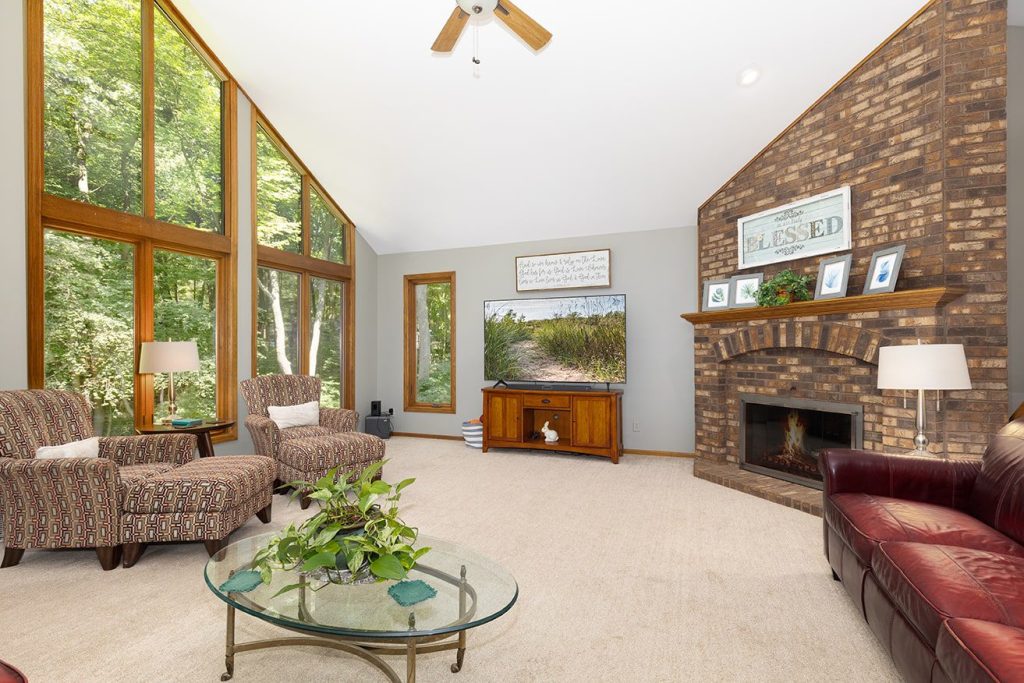 Inviting living room with large windows revealing a tree-shaded yard, ideal for builders, remodelers, and designers.